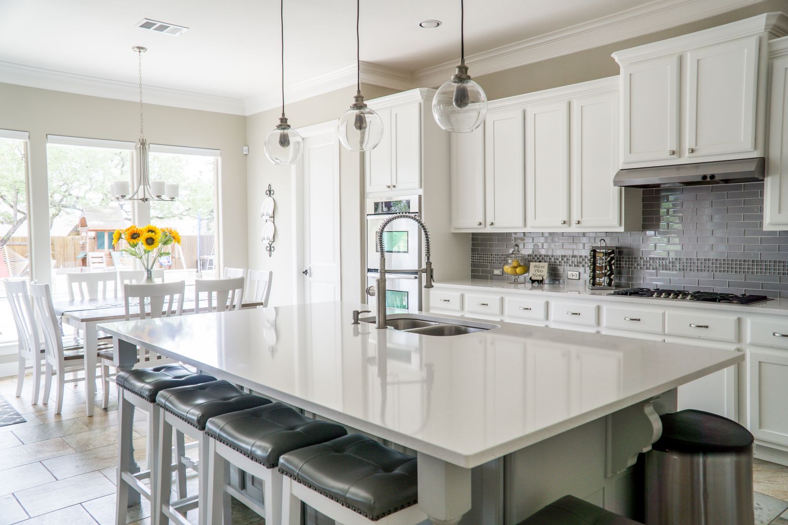 A bright renovated kitchen with white cabinetry, an island, and tiled floor.